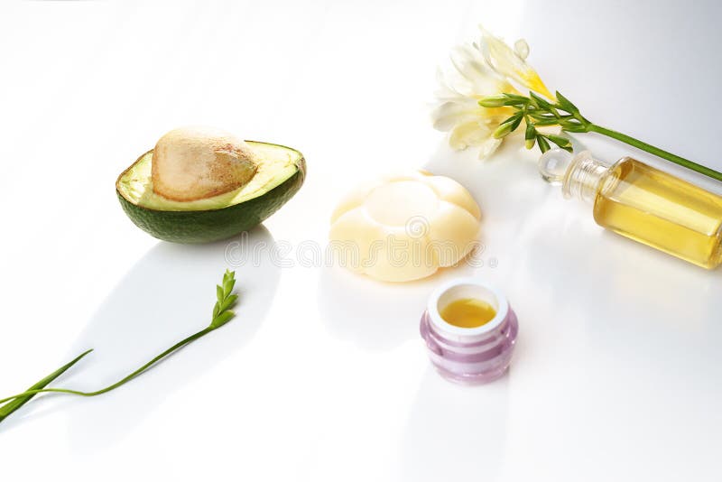 Beauty concept avocado skin care facial essence oil, soap, lily flower and towel on white background. Facial treatment preparation