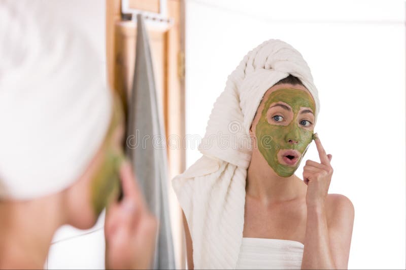 Beauty concept. The woman applies green organic face mask in the bathroom