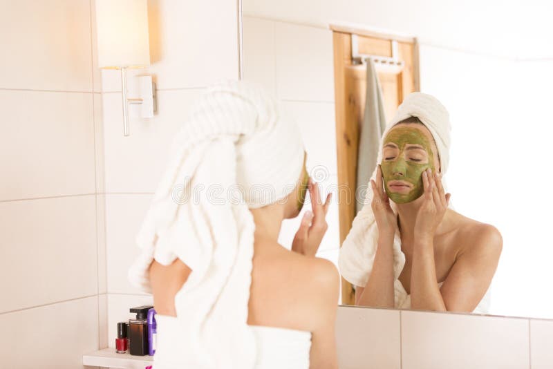 Beauty concept. The woman applies green organic face mask in the bathroom