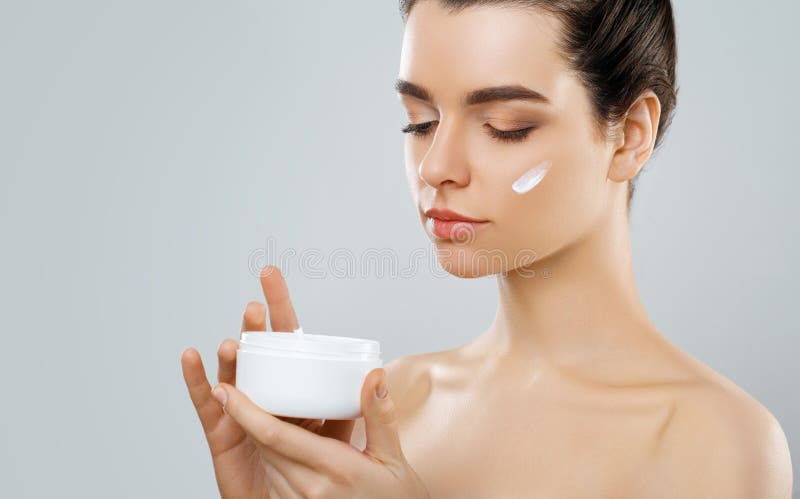 Beauty Concept. woman holds a moisturizer in her hand and spreads it on her face to moisturize her skin