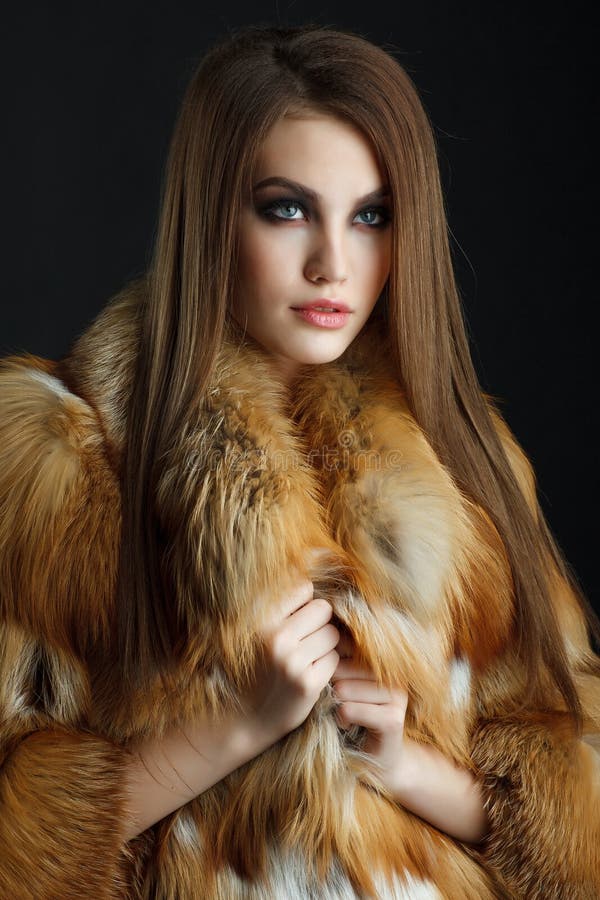 Beautiful girl with dark hair wearing fashion red fur coat Stock