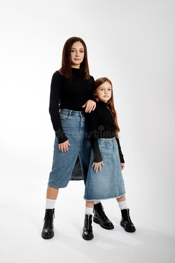 Beauty fashion portrait mother and daughter in a black turtleneck and blue denim skirt. Woman and girl, family