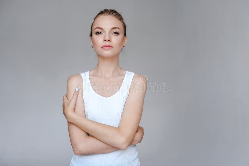 Beauty fashion portrait young woman with clear skin  in white clothes hugged herself