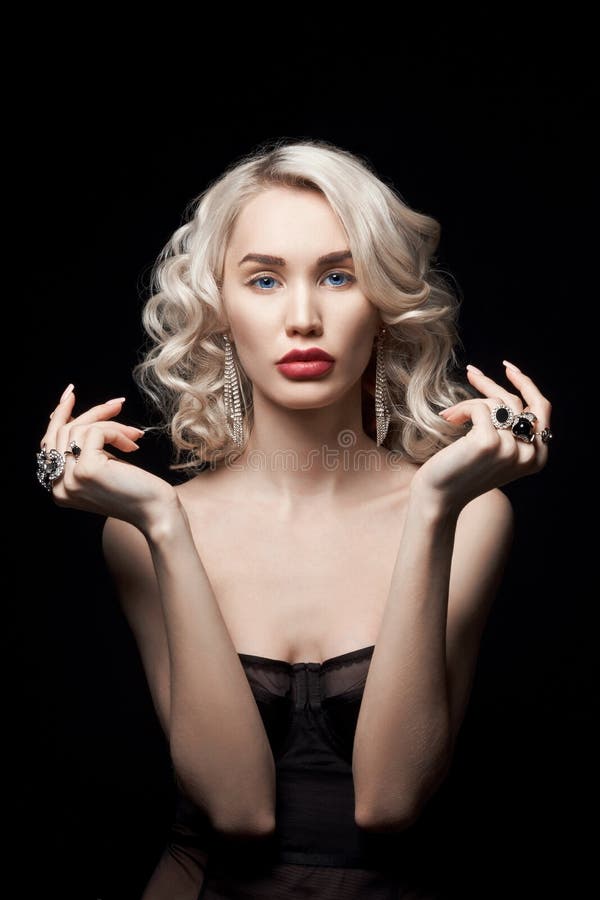 Beauty fashion woman with jewelry on her hands, wavy hair. Portrait of a blonde girl with rings on her fingers, beautiful makeup