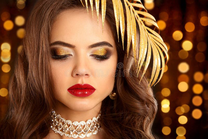 Beauty golden eye makeup. Fashion brunette portrait in gold. Sex