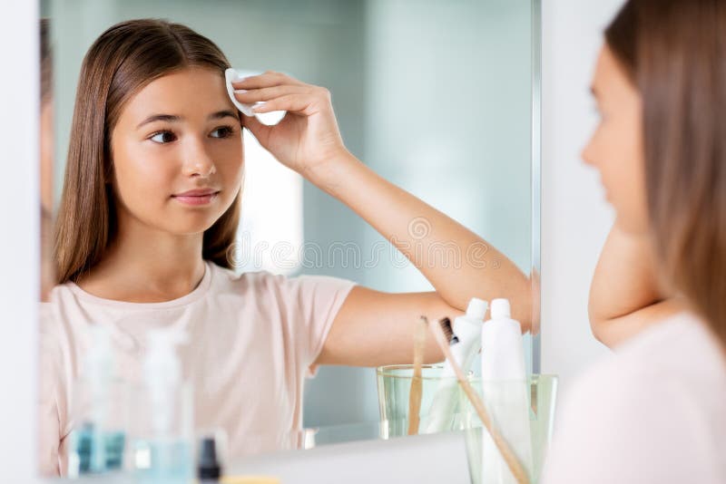 teenage girl cleaning face skin with cotton disc