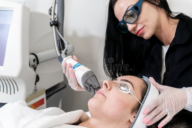 Beauty laser technician performing skin resurfacing procedure in a medical spa and beauty clinic. Caucasian female patient