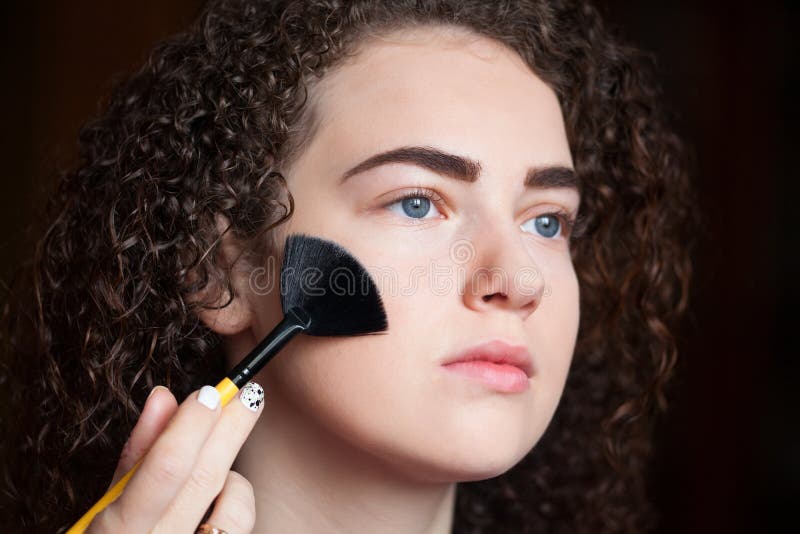 Closeup portrait of beautiful woman getting professional make-up with brush royalty free stock photo Closeup portrait of beautiful woman getting professional make-up with brush royalty free stock photo