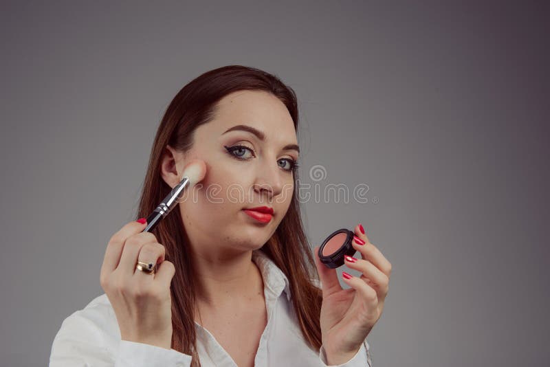 Beauty model teenage girl looking in the mirror and applying mascara make up. Beautiful young woman apply makeup