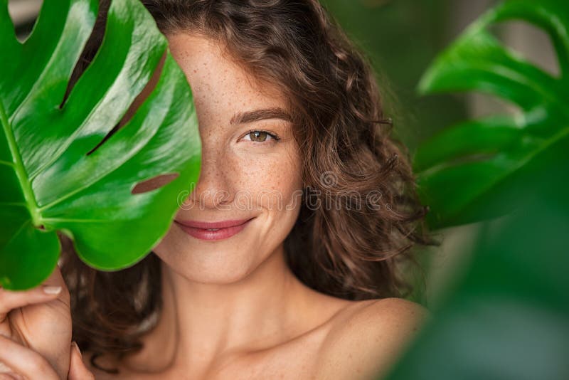 Beauty natural woman covering her face with tropical leaf