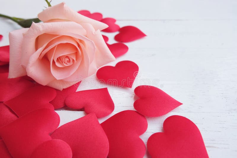 Beauty pink-orange rose and red satin hearts shape on wooden floor. Valentine&x27;s day background concept