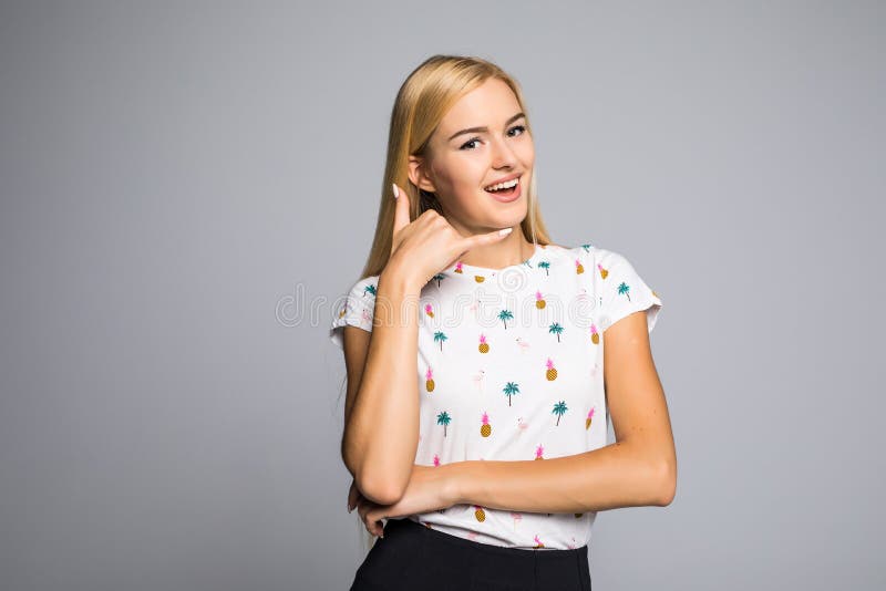 Beauty portrait of blonde woman with call me back gesture on gray