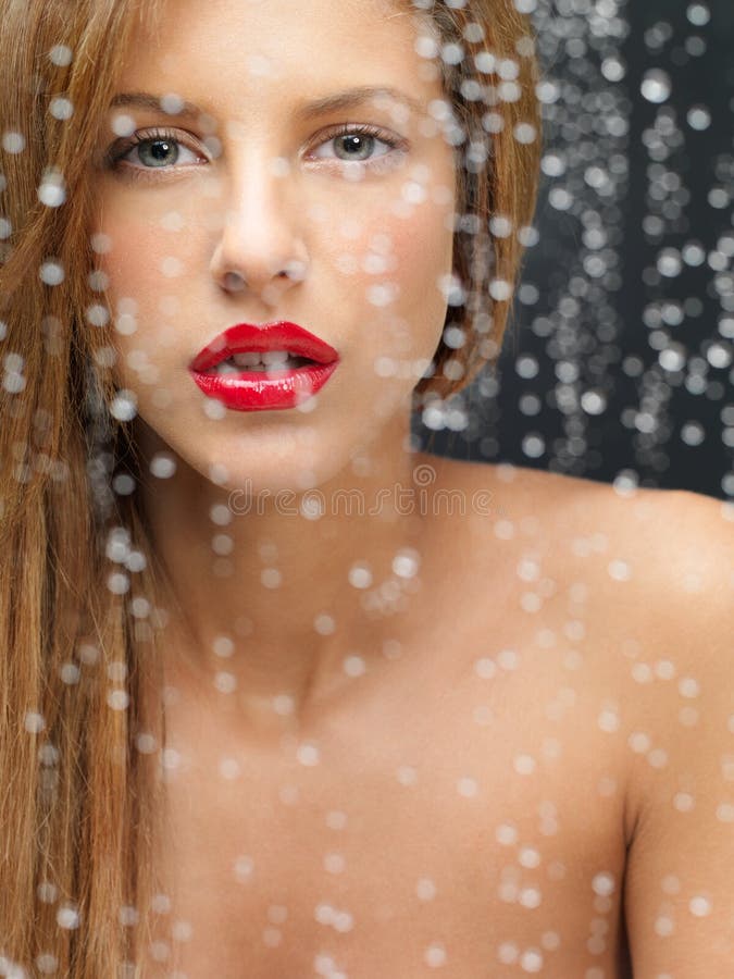 Beauty portrait of woman behind wet window