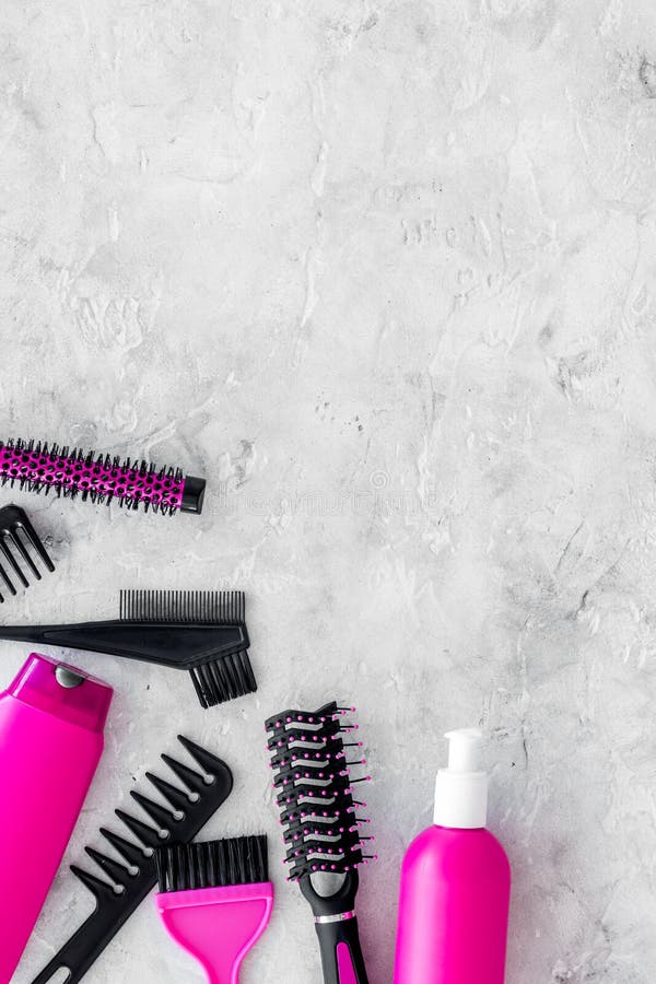 Beauty salon pink work tools with comb for hair dress and coloring on stone background top view mock up