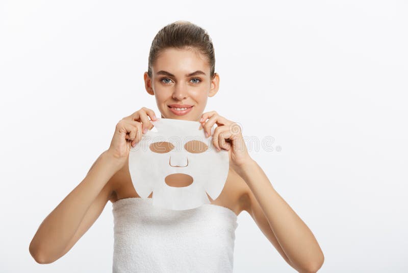 Beauty Skin Care Concept - Beautiful Caucasian Woman applying paper sheet mask on her face white background. stock photography Beauty Skin Care Concept - Beautiful Caucasian Woman applying paper sheet mask on her face white background. stock photography