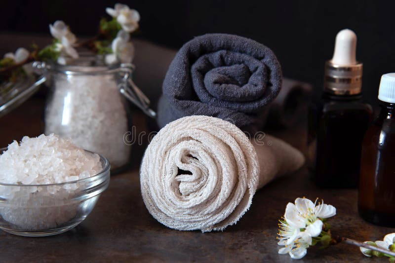 Beauty spa treatment and relax concept. Towel, sea salt and essential oils on a dark background