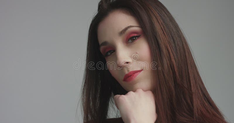 Beauty spanish woman in red dress with vivd red eye makeup looking at camera