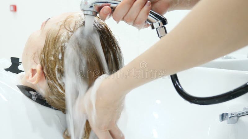 Beauty studio. Washing woman hair with shampoo, Make-up and beauty salon. Close up hand of hairdresser washing hair on stock footage