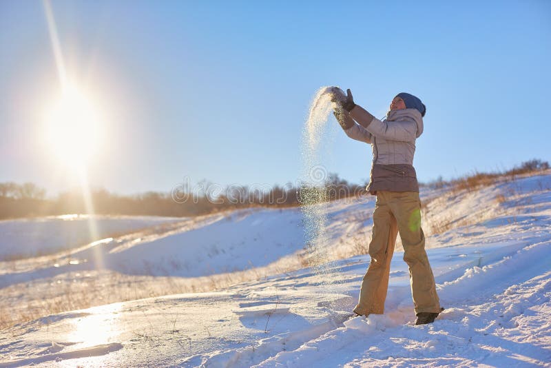 Beauty Winter Girl Blowing Snow in frosty winter Park. Outdoors. Flying Snowflakes. Sunny day. Backlit. Beauty young woman Having royalty free stock image Beauty Winter Girl Blowing Snow in frosty winter Park. Outdoors. Flying Snowflakes. Sunny day. Backlit. Beauty young woman Having royalty free stock image
