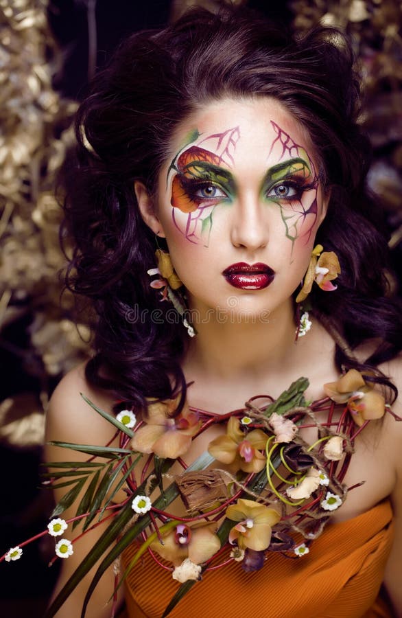 Beauty woman with face art and jewelry from flowers orchids