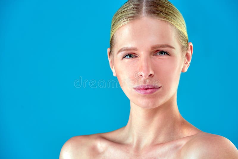 Beauty Woman face Portrait. Beautiful Spa model Girl with Perfect Fresh Clean Skin. Blonde female looking at camera and smiling. Youth and Skin Care Concept.Blue background gray