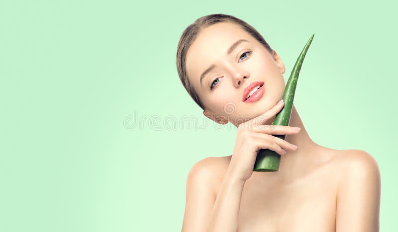 Beauty woman with perfect skin holding fresh leaf of Aloe Vera. Portrait of beautiful brunette spa girl. Skincare
