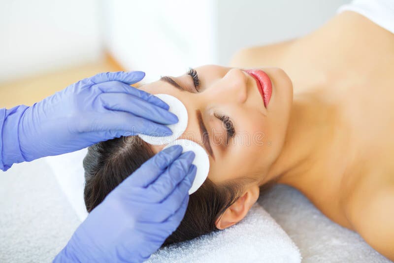 Beauty. Young Girl in Beauty Salon. Cosmetologist Cleans the Skin of the Face with Cotton Pads. Lying on the Massage. Make, treatment.