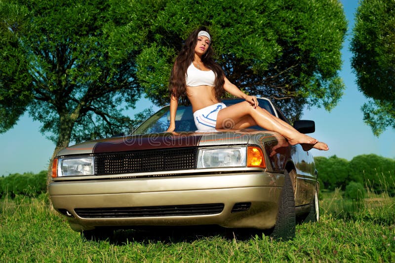 Beauty young girl washing a car at summer sunset