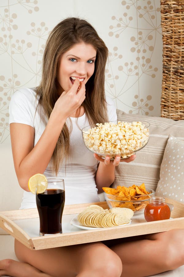 Beauty young woman sitting on sofa and having dinn