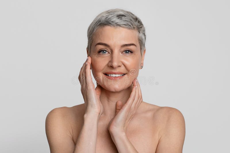 Beauté mûre. Portrait de la belle femme entre deux âges nue touchant sa peau lisse photographie stock libre de droits