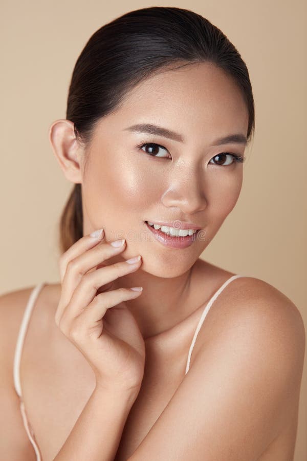 Beauté. Portrait asiatique de femme. Magnifique modèle touchant le visage et regardant la caméra. Fille de charme avec la peau sai image stock