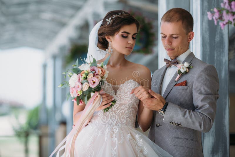 Beaux couples de mariage étreignant en parc avec les arbres verts sur le fond Marié dans un costume gris d'affaires, chemise blan image stock Beaux couples de mariage étreignant en parc avec les arbres verts sur le fond Marié dans un costume gris d'affaires, chemise blan image stock