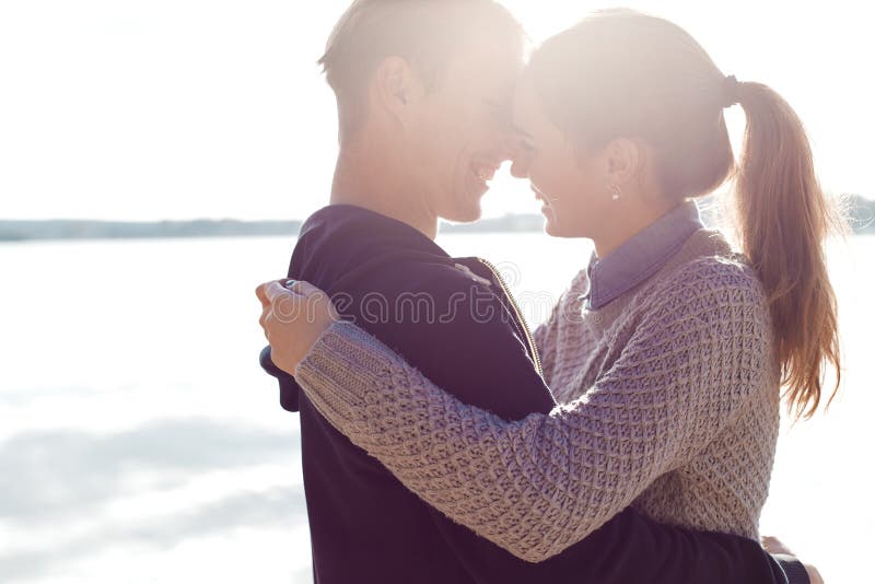 Beaux jeunes couples dans l'amour marchant sur le rivage du lac au coucher du soleil dans les rayons de la lumière lumineuse image stock Beaux jeunes couples dans l'amour marchant sur le rivage du lac au coucher du soleil dans les rayons de la lumière lumineuse image stock