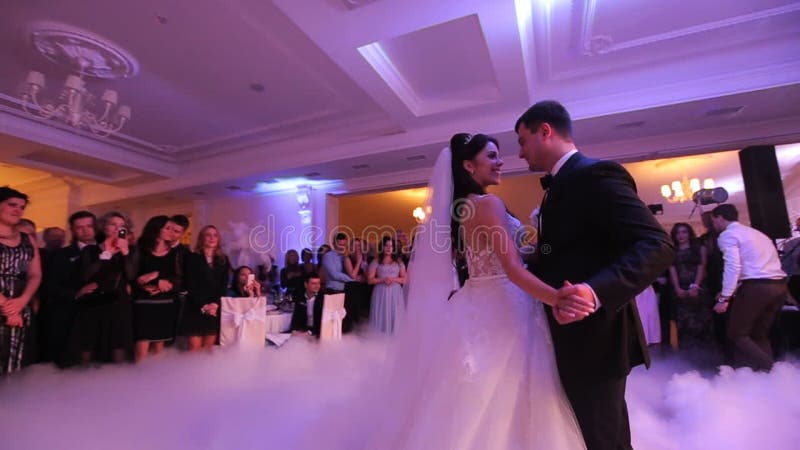 Beaux jeunes nouveaux mariés dansant leur première danse enveloppée par la vapeur blanche Célébration de mariage dans le restaura