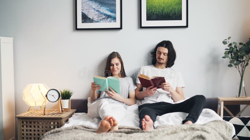 Beaux livres de lecture de couples se reposant dans le lit à la maison appréciant ensemble le passe-temps clips vidéos