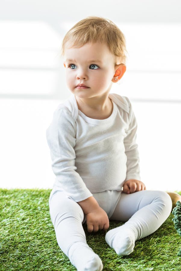 Feliz Bebê Loira Com Duas Pequenas Tranças Em Camiseta Branca E Um Kit De  Calças Jeans Sentado Sobre O Fundo Da Grama Verde Foto de Stock - Imagem de  pouco, inocência: 143643548