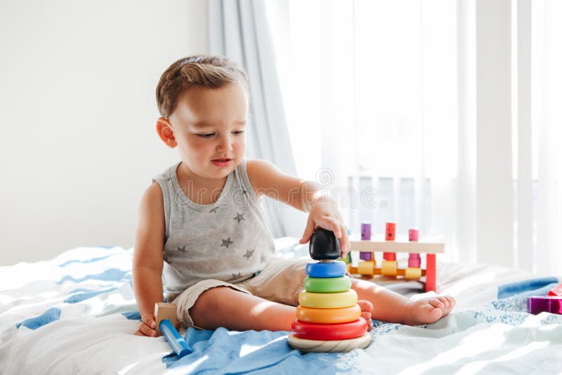 Mãe brincando com o jogo de pirâmide de bebê de 1 ano sentado em casa