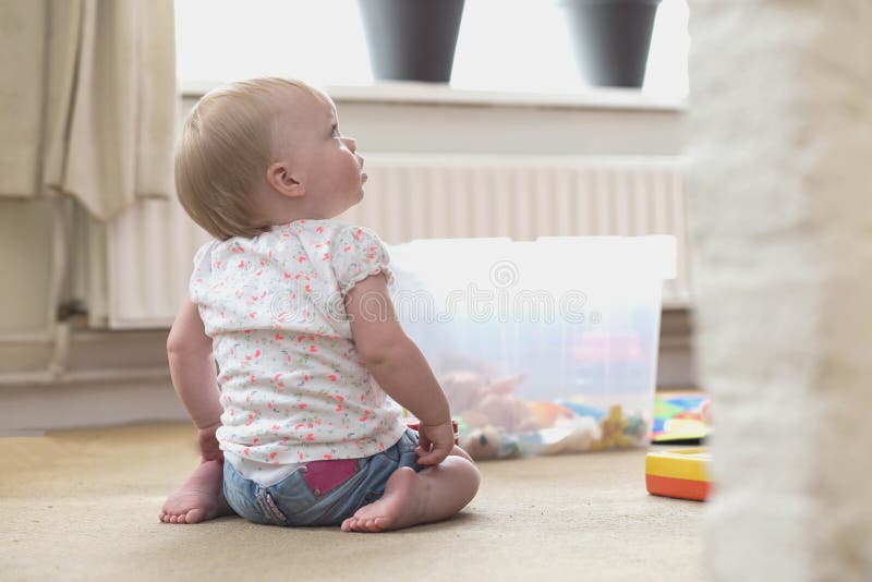 Beb? que joga apenas com brinquedos em um tapete no assoalho em casa foto de stock royalty free Beb? que joga apenas com brinquedos em um tapete no assoalho em casa foto de stock royalty free