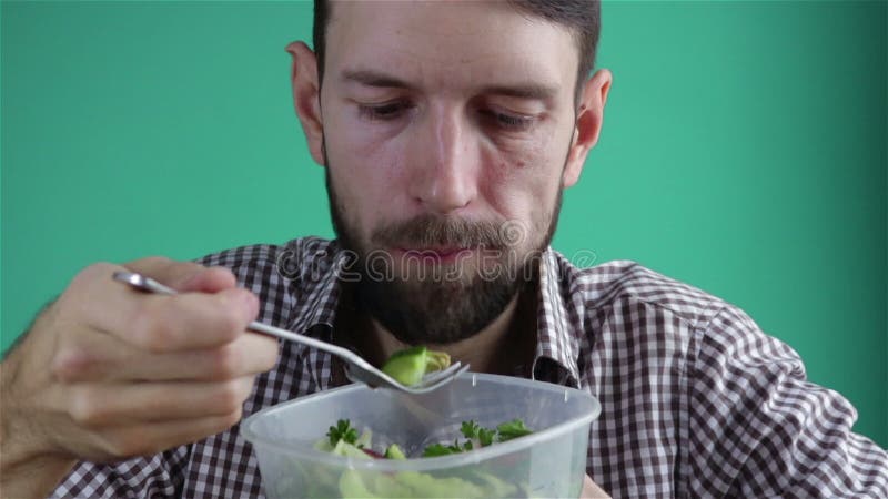 Bebaard man die gezonde vegetarische sla eet uit plastic verpakking