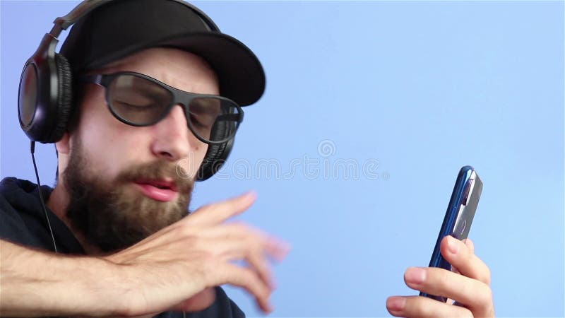 Bebaard man met een koptelefoon zonnebril die video's bekijkt en op smartphone live streaming online vertaalclos speelt