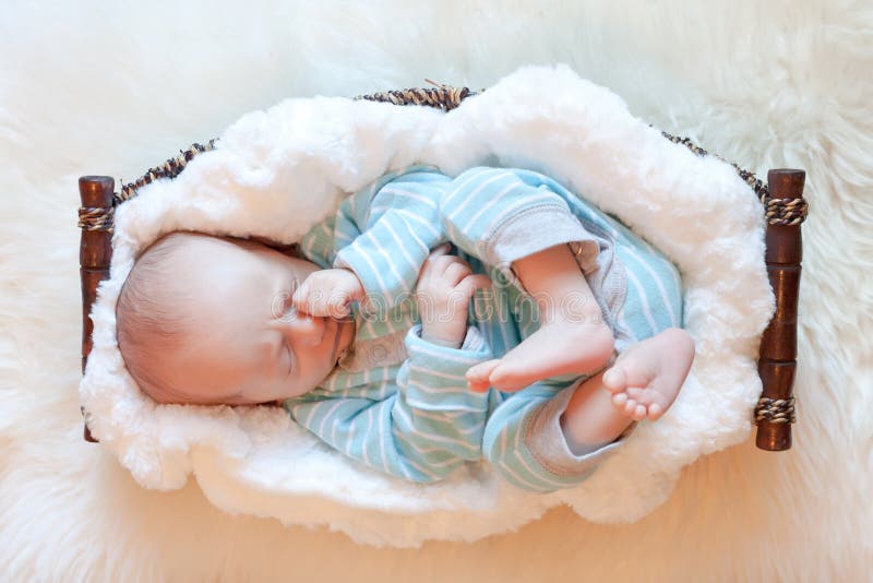 Bebeluș adormit în coș pe pătură albă moale stock photos