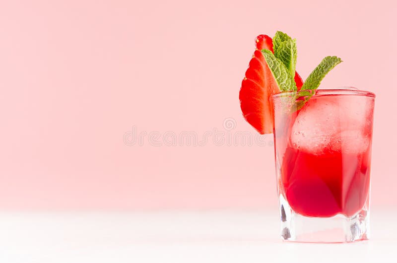 Bebida alcohólica roja brillante en vaso de medida con la rebanada de la fresa, cubos de hielo, menta verde en la barra moderna d imágenes de archivo libres de regalías Bebida alcohólica roja brillante en vaso de medida con la rebanada de la fresa, cubos de hielo, menta verde en la barra moderna d imágenes de archivo libres de regalías