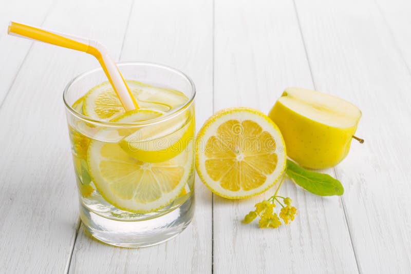Bebida de restauración para la desintoxicación, agua del limón en una manzana de cristal, fresca y flores amarillas del tilo en u foto de archivo Bebida de restauración para la desintoxicación, agua del limón en una manzana de cristal, fresca y flores amarillas del tilo en u foto de archivo