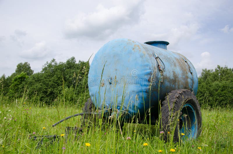 Blue water cistern for animal stand between pasture grass and clovers move in wind. Blue water cistern for animal stand between pasture grass and clovers move in wind.