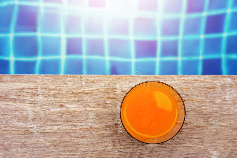 Bebida do verão na piscina Vidro do suco de laranja no fotografia de stock Bebida do verão na piscina Vidro do suco de laranja no fotografia de stock