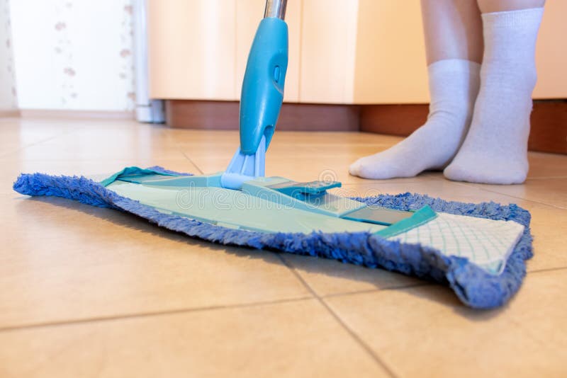 Bebouwd beeld van mooie jonge vrouw die een blauwe zwabber gebruiken terwijl het schoonmaken van de vloer in keuken royalty-vrije stock afbeeldingen Bebouwd beeld van mooie jonge vrouw die een blauwe zwabber gebruiken terwijl het schoonmaken van de vloer in keuken royalty-vrije stock afbeeldingen