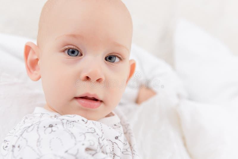 Bebé adorable con los ojos azules que miran directamente la cámara que intenta alcanzar para ella Cierre lindo del niño para arri fotos de archivo Bebé adorable con los ojos azules que miran directamente la cámara que intenta alcanzar para ella Cierre lindo del niño para arri fotos de archivo