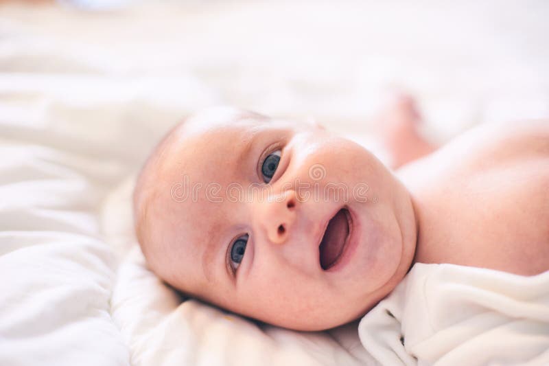 Bebé adorable en el dormitorio soleado blanco Niño del niño recién nacido que se relaja en cama fotografía de archivo Bebé adorable en el dormitorio soleado blanco Niño del niño recién nacido que se relaja en cama fotografía de archivo