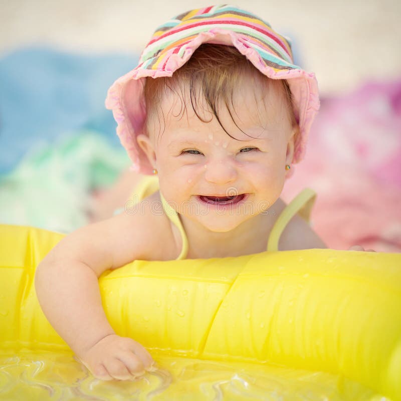 Bebé alegre con el síndrome de los plumones que juega en la piscina