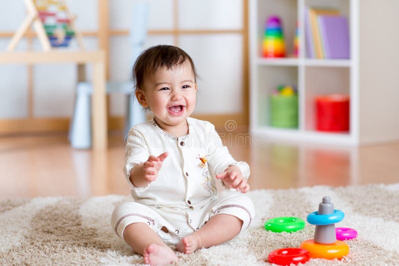 Bebé alegre lindo que juega con el juguete colorido en casa imagen de archivo